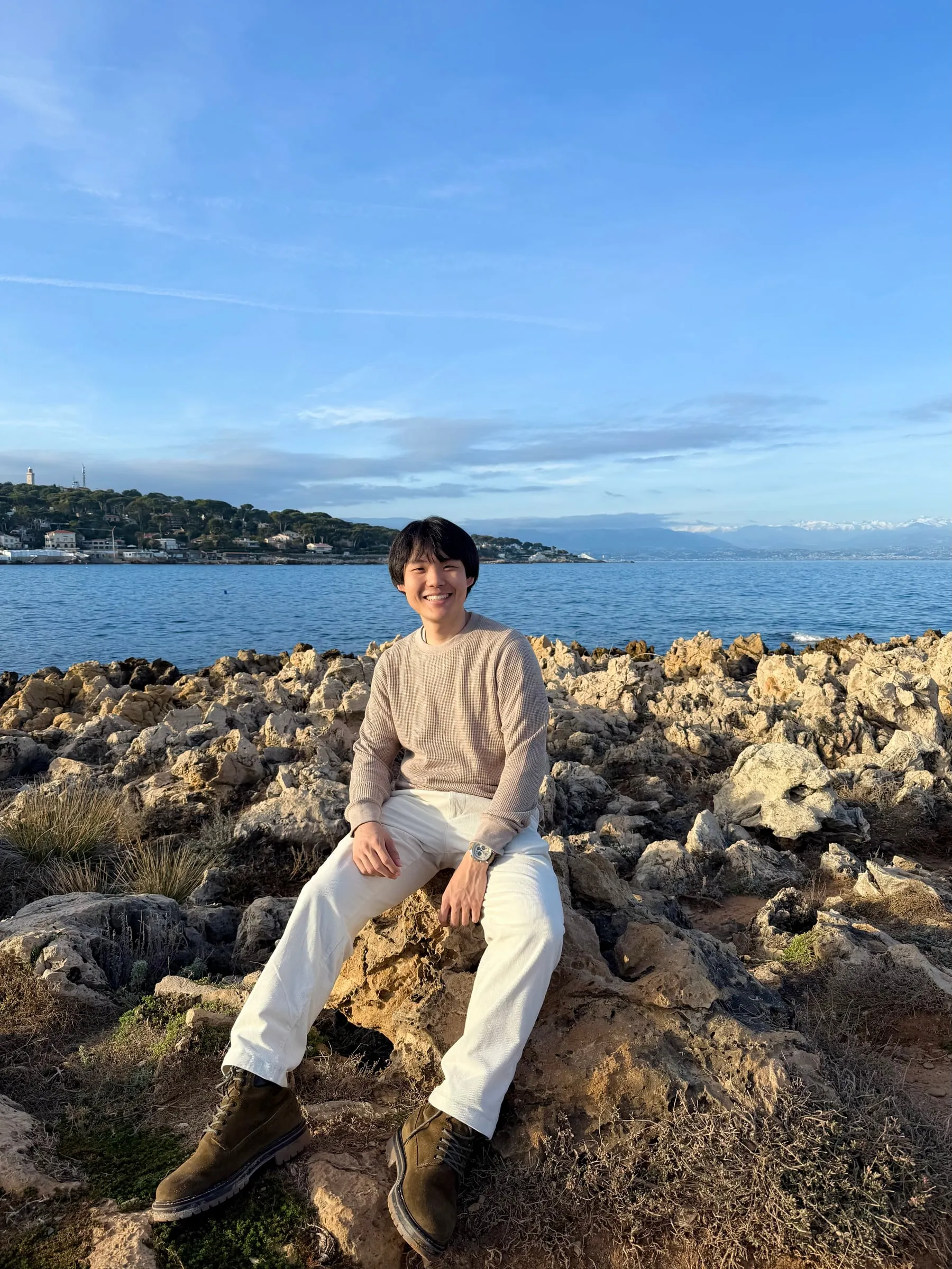 Alan sitting on seaside rocks in late afternoon light