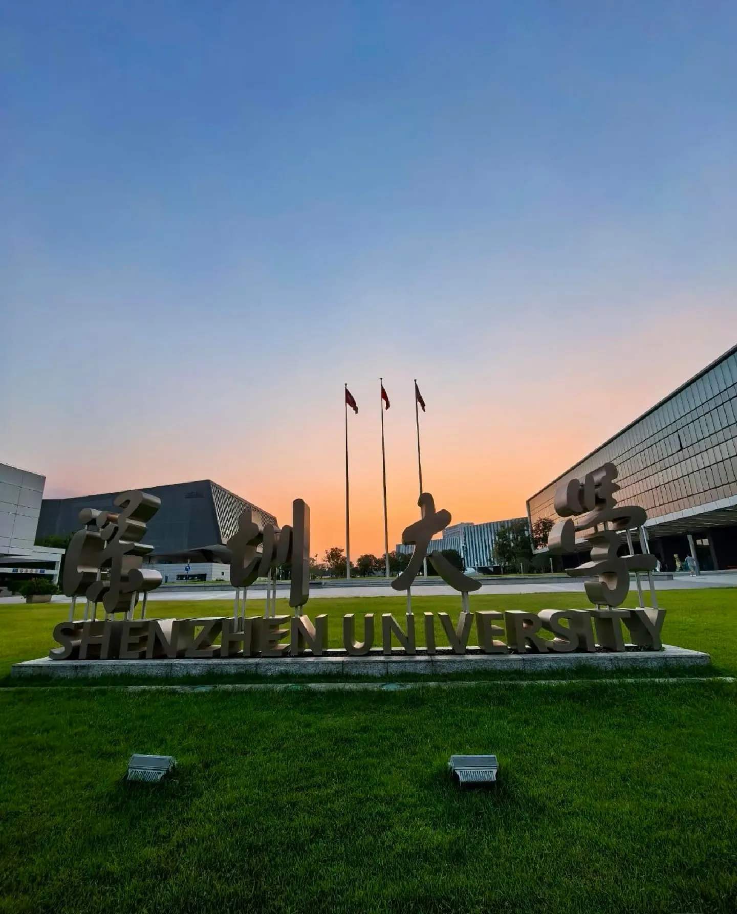 Shenzhen University sign on the campus lawn at sunset